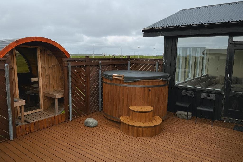 Outdoor hot tub and wooden sauna at Hafnir Guesthouse